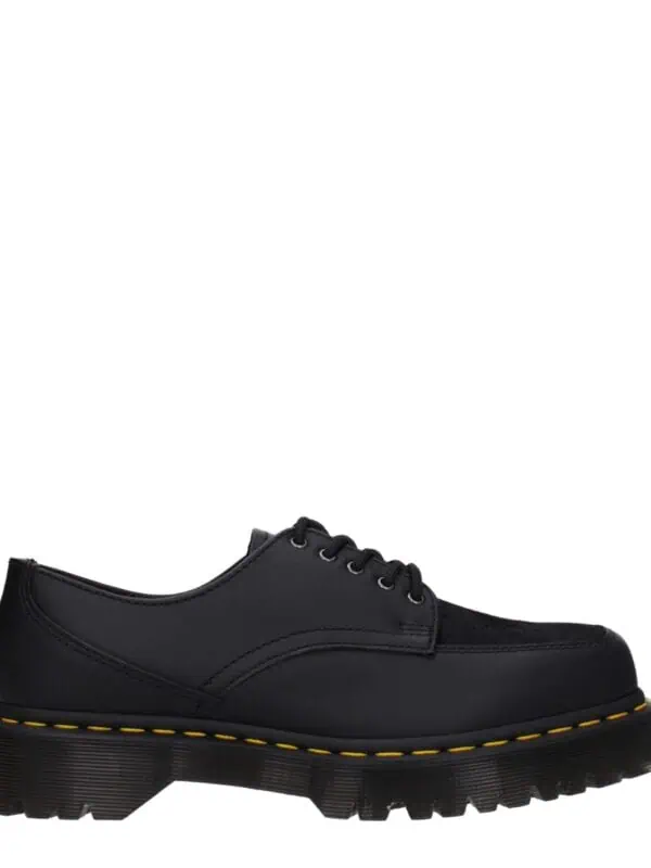 Black leather lace-up rugged shoes with chunky sole and yellow stitching for men and women.