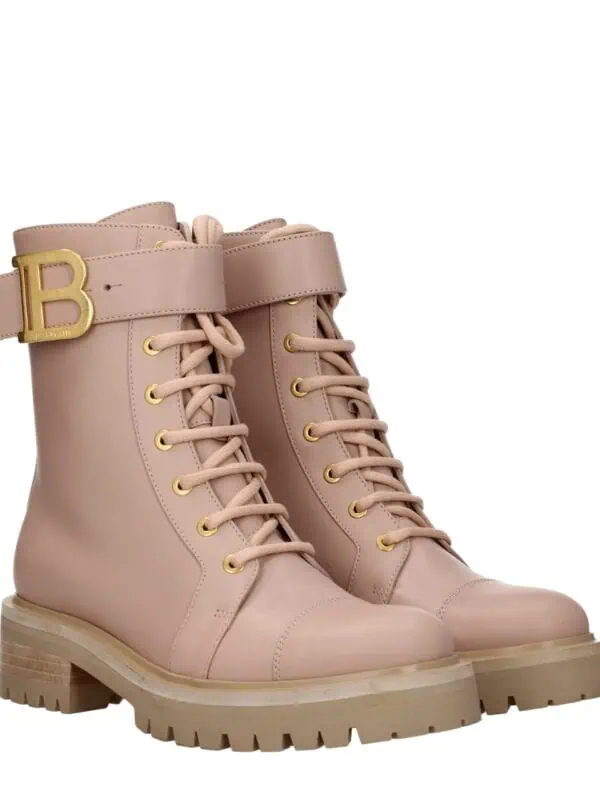 Pink leather lace-up combat boots with beige chunky soles and gold eyelets, featuring a wide strap with a gold "B" buckle for a luxury touch.