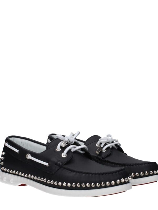 Black leather studded designer loafers with white laces and metallic accents for luxury fashion and casual wear. High-quality craftsmanship with bold style elements. Perfect for statement footwear.