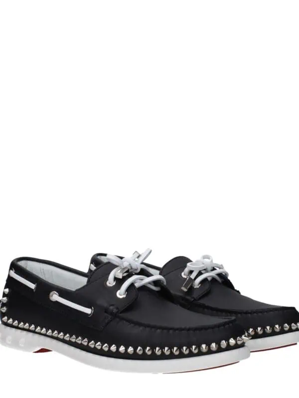Black leather studded designer loafers with white laces and metallic accents for luxury fashion and casual wear. High-quality craftsmanship with bold style elements. Perfect for statement footwear.
