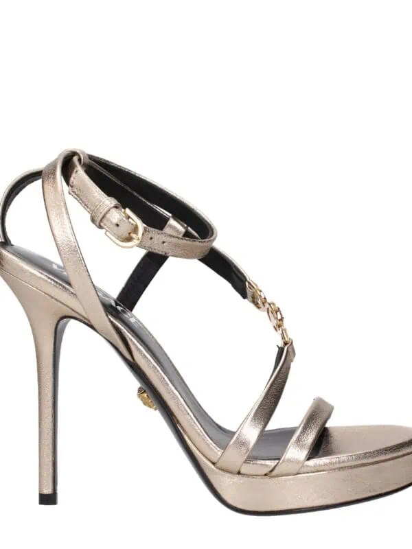 Elegant metallic gold high-heel sandal with ankle strap and decorative chain detail, perfect for stylish occasions and evening wear.