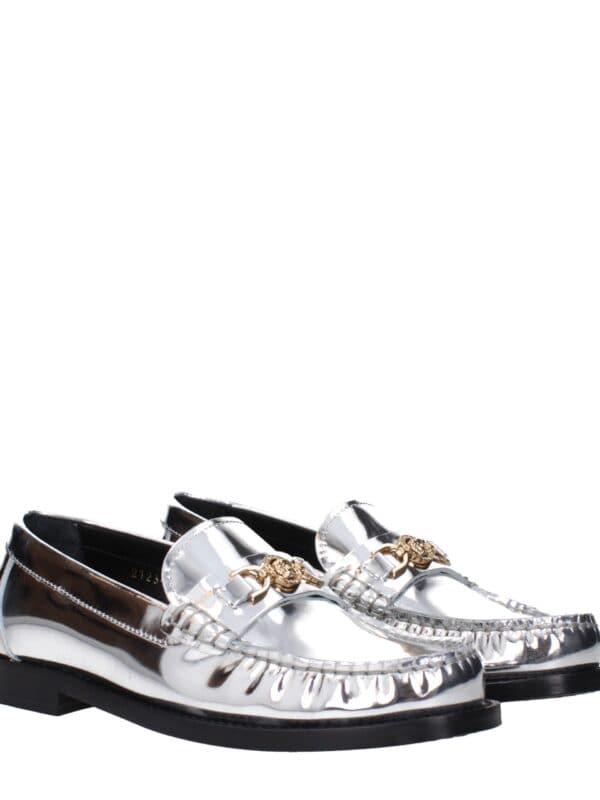 Reflective silver loafers with gold-tone emblem details, slip-on design, and black rubber soles, perfect for a luxurious and fashionable look.