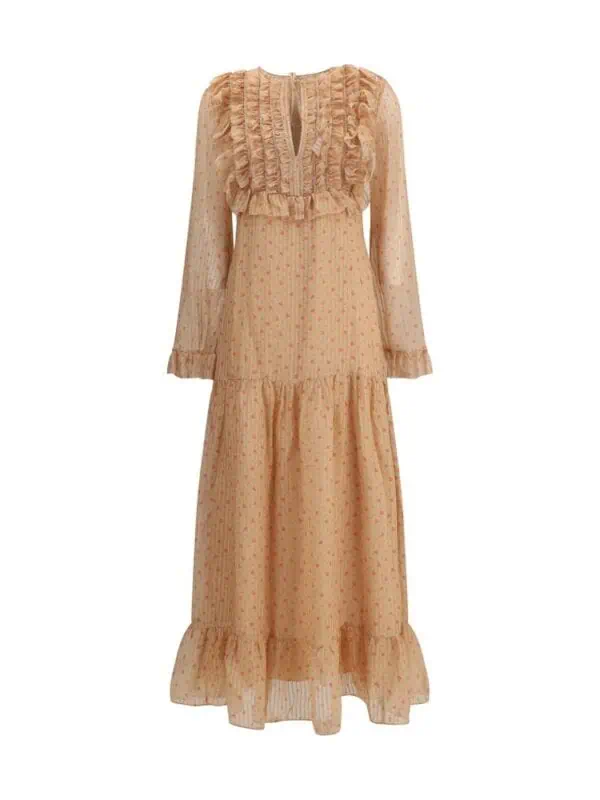 Flowy beige maxi dress with ruffled detailing, polka dot pattern, and semi-sheer long sleeves perfect for boho-chic fashion and elegant occasions.