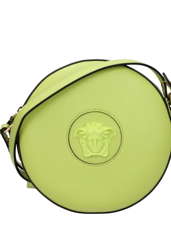 Vivid lime green round designer shoulder bag with Medusa logo embossed on the front, featuring black piping and gold hardware, perfect for a stylish statement accessory.