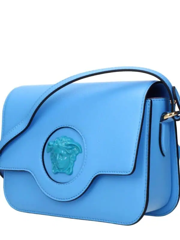 Vibrant blue luxury handbag with a Medusa emblem, featuring gold accents and a structured silhouette ideal for fashion-forward accessories.