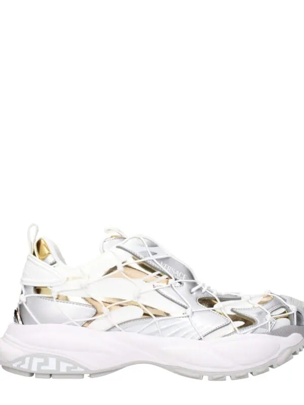 White and gold Versace luxury sneakers with intricate design and bold branding for high-end fashion statement.