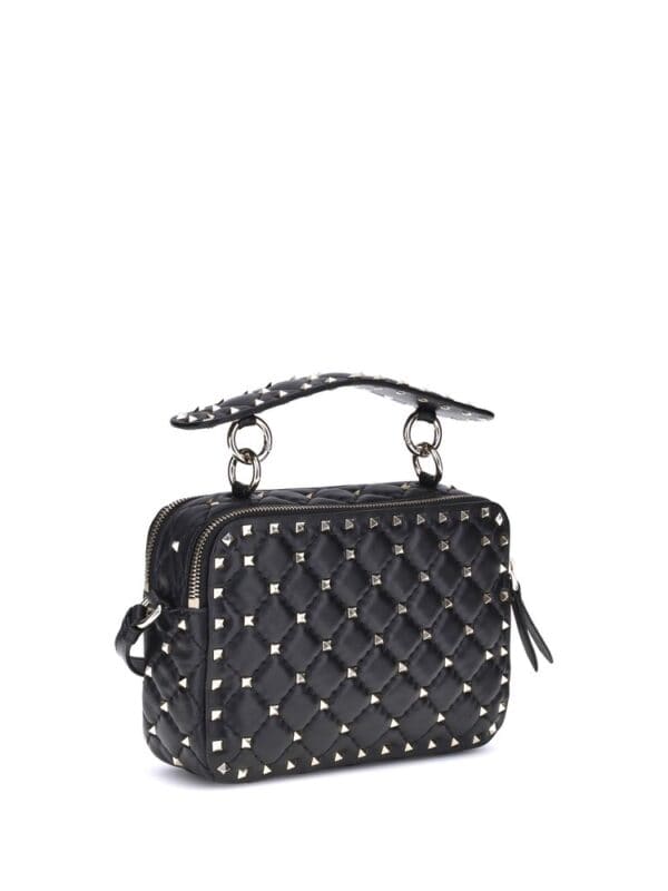 Crafted black quilted handbag with silver stud accents, top handle, and zipper closure, perfect for a stylish and edgy look.