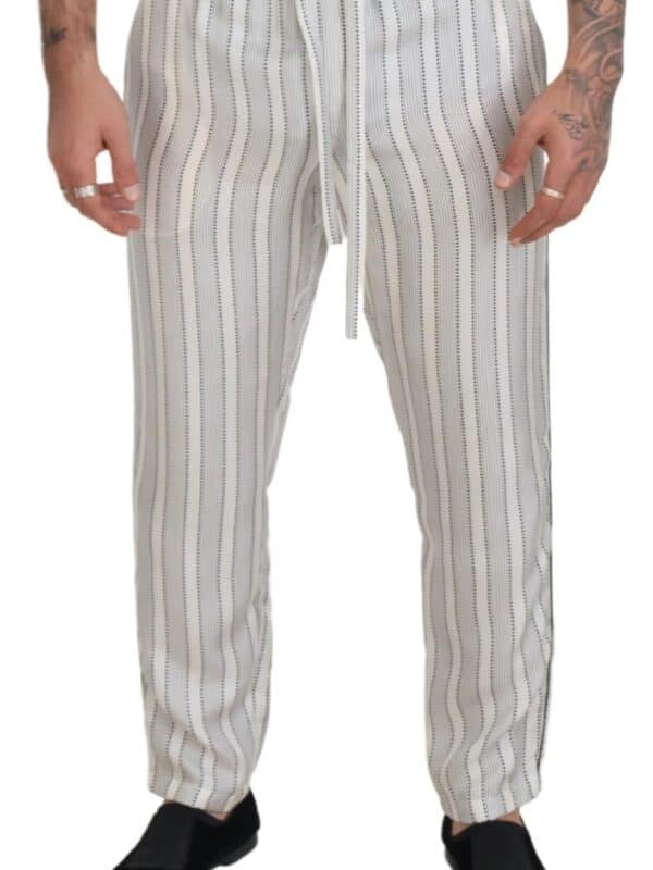 Silk pants with vertical stripe pattern, drawstring waist, and relaxed fit, perfect for stylish casual wear or loungewear, showcased on a model with tattoos and rings from Lux Brands.