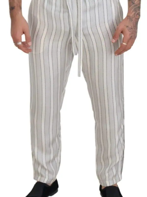 Silk pants with vertical stripe pattern, drawstring waist, and relaxed fit, perfect for stylish casual wear or loungewear, showcased on a model with tattoos and rings from Lux Brands.